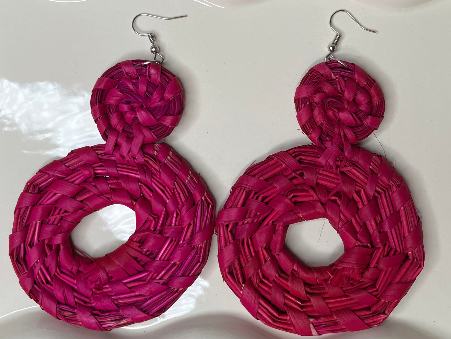 Pink woven earrings on a white dish