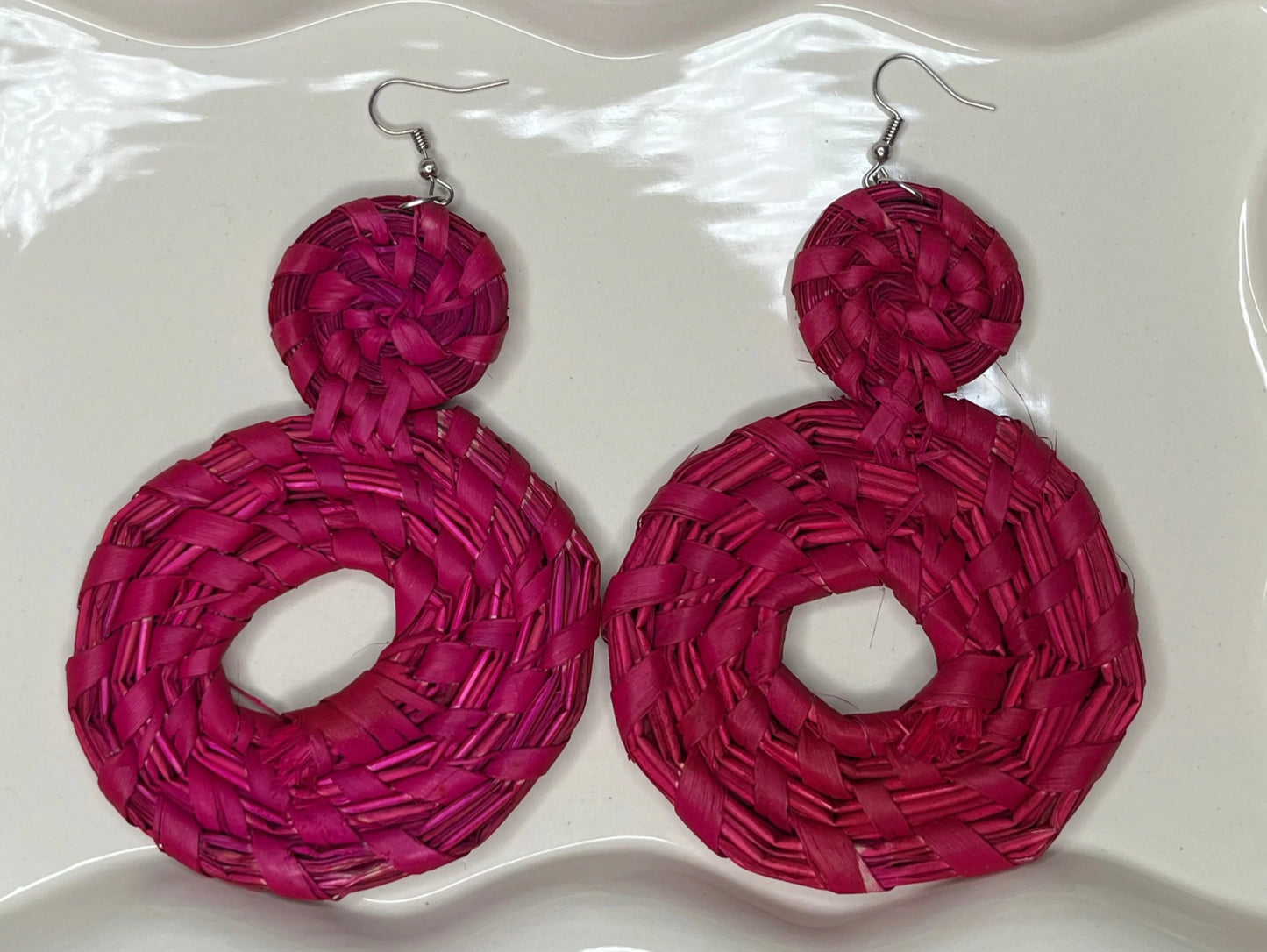 Pair of pink earrings on a white dish