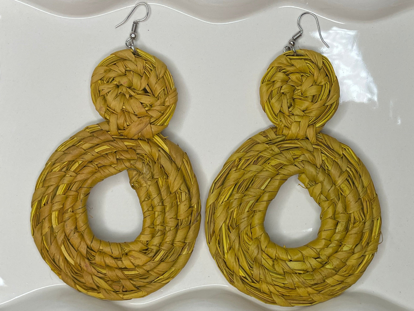 Pair of yellow circular earrings on a white decorative plate.