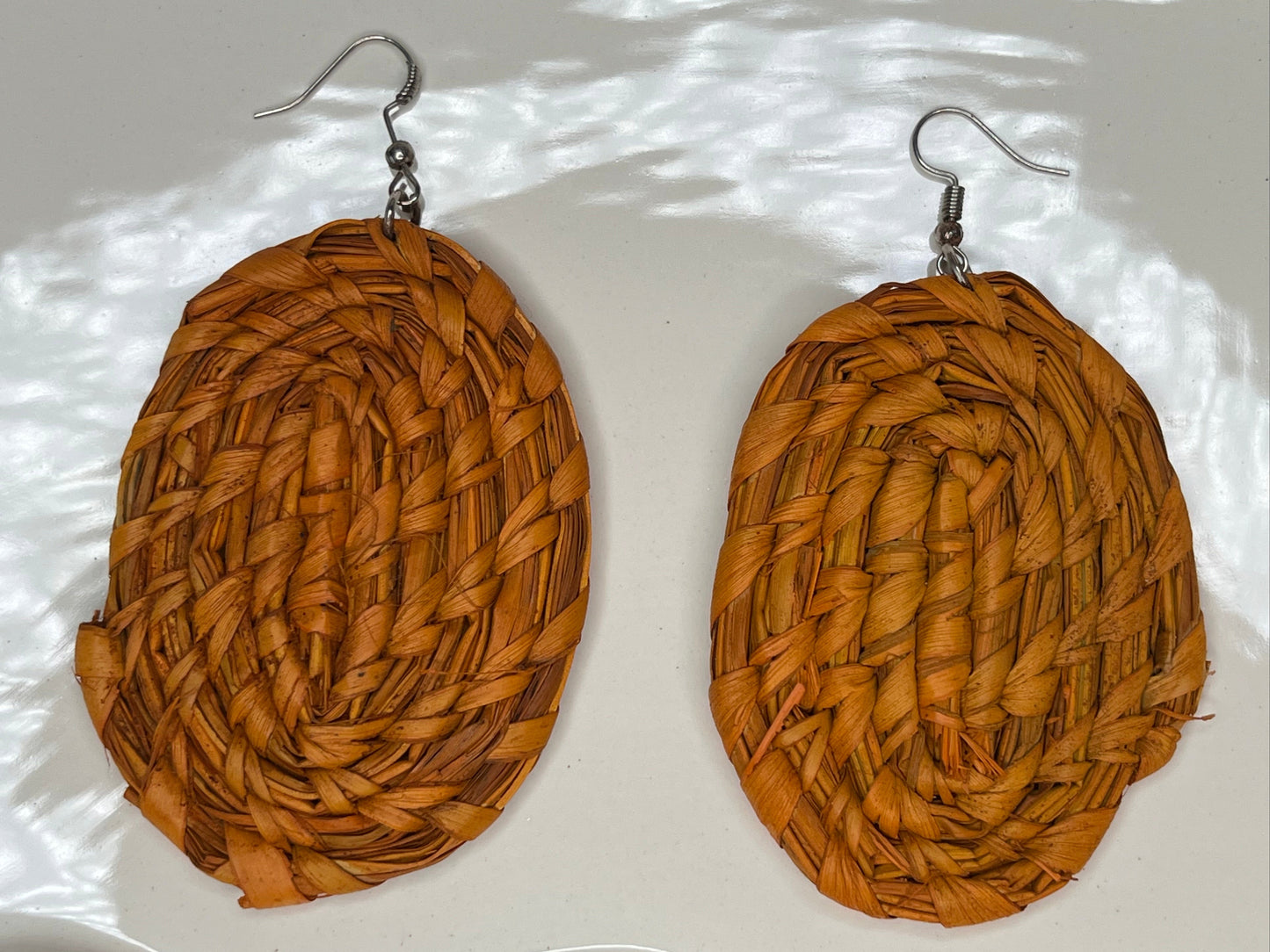 Brown woven earrings on a textured white surface