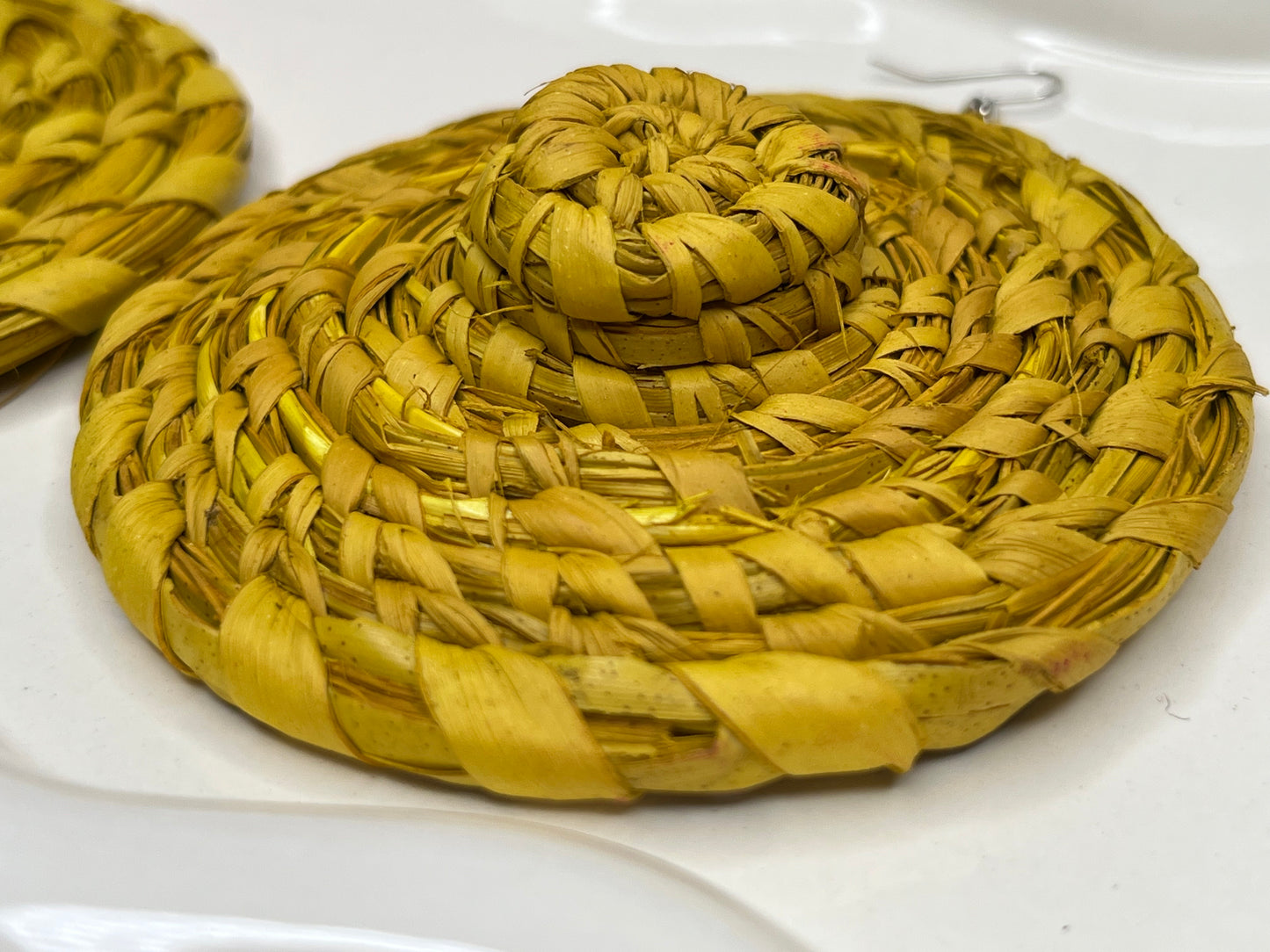 Yellow woven earrings on a white surface