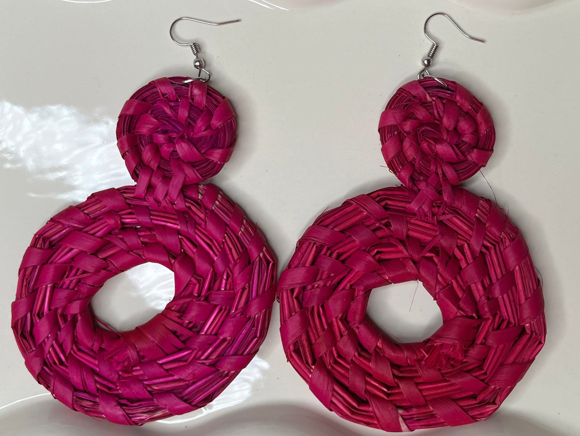 Pink woven earrings on a white dish