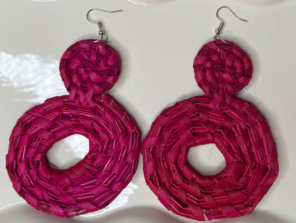 Pink woven earrings on a white dish