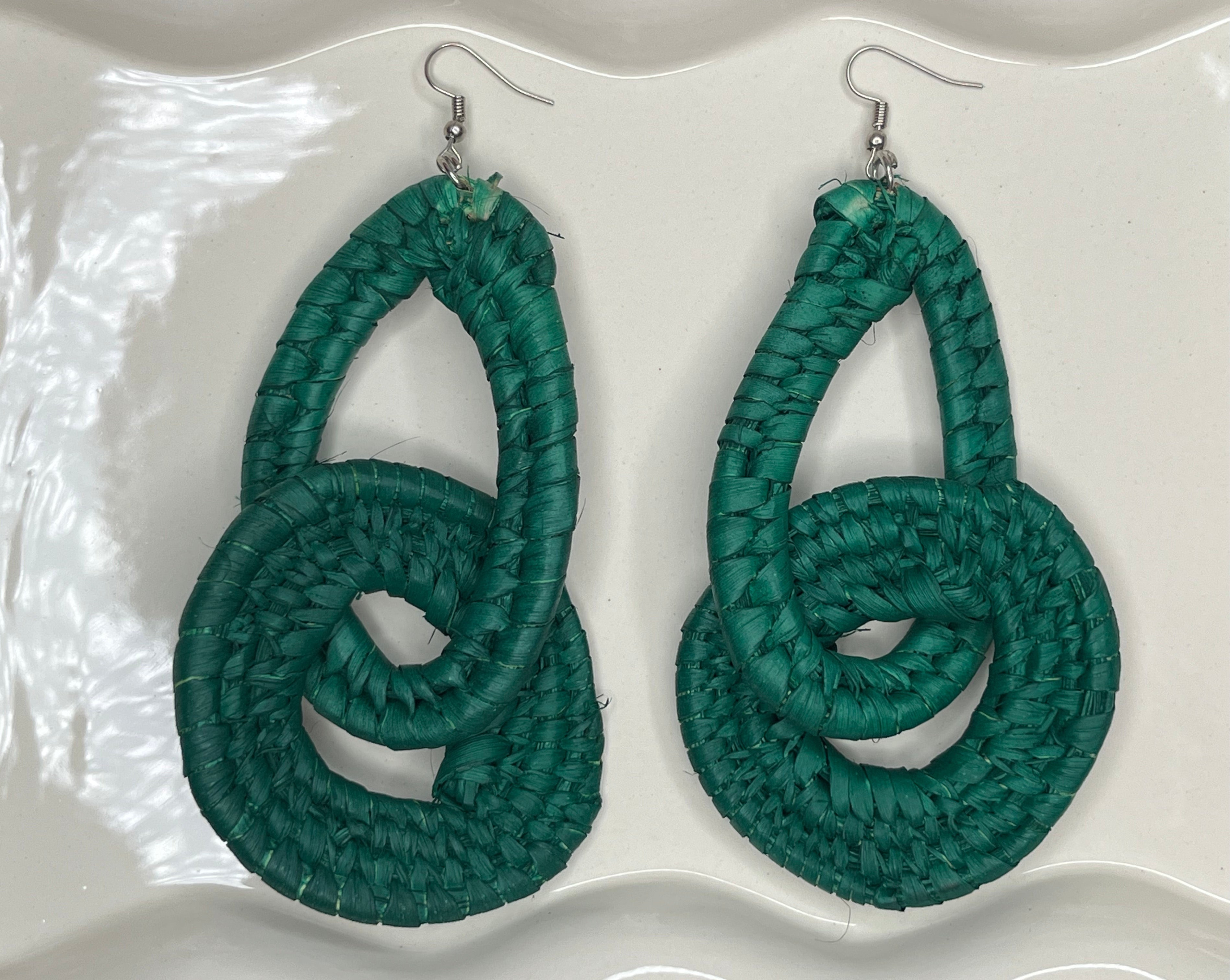 Pair of green knotted raffia earrings on a white background