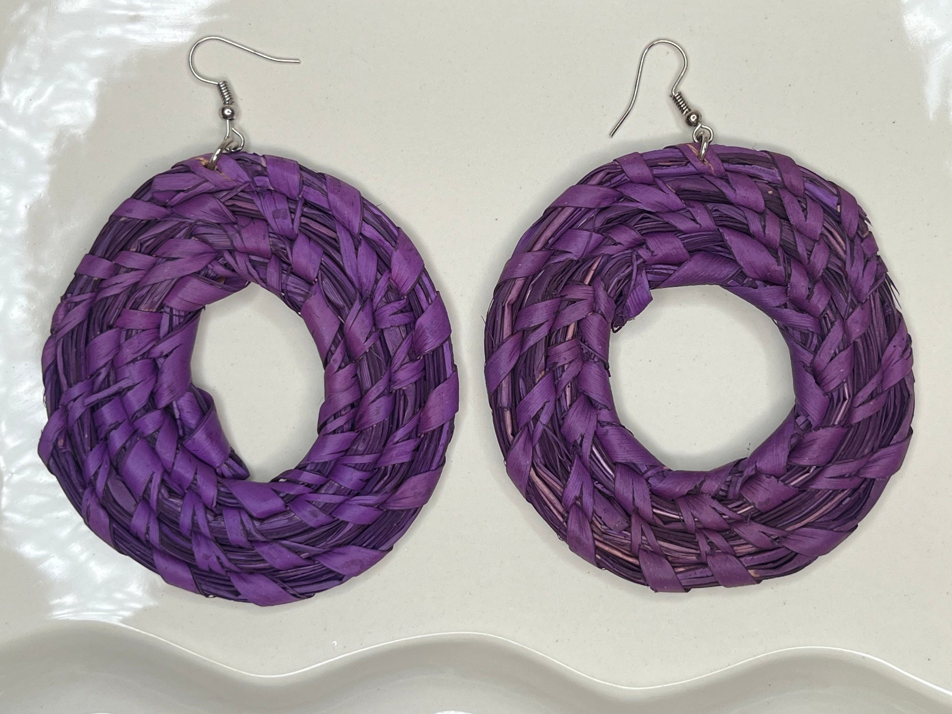 Purple braided hoop earrings on a white background